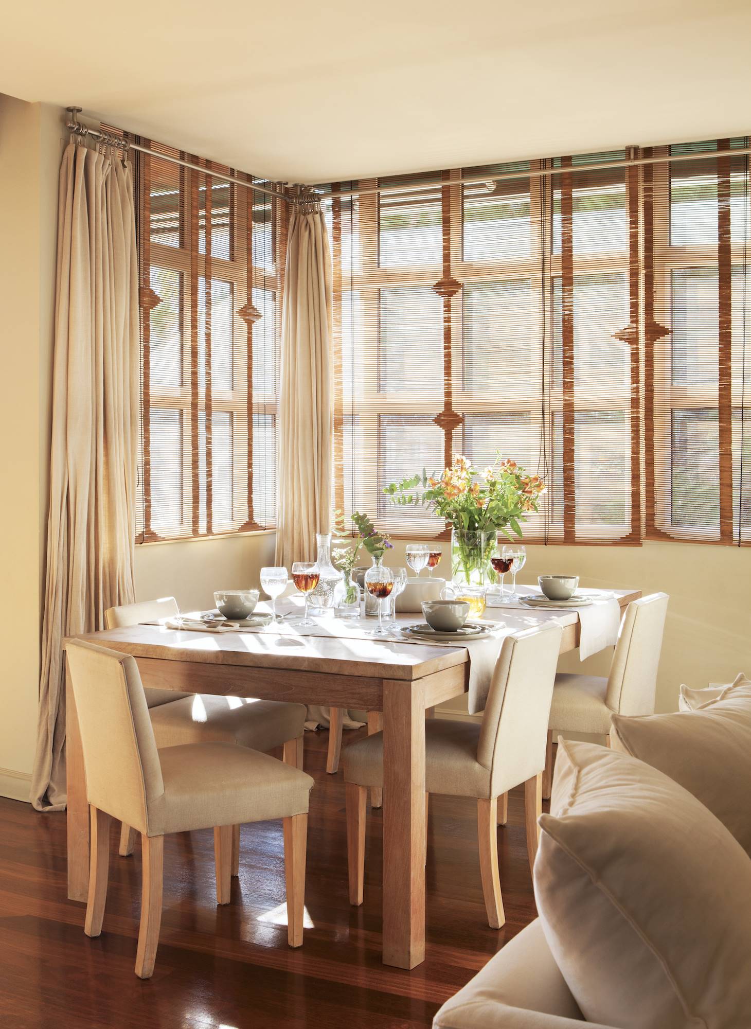 Comedor con paredes y sillas tapizadas en beige y mesa de comedor de madera. 