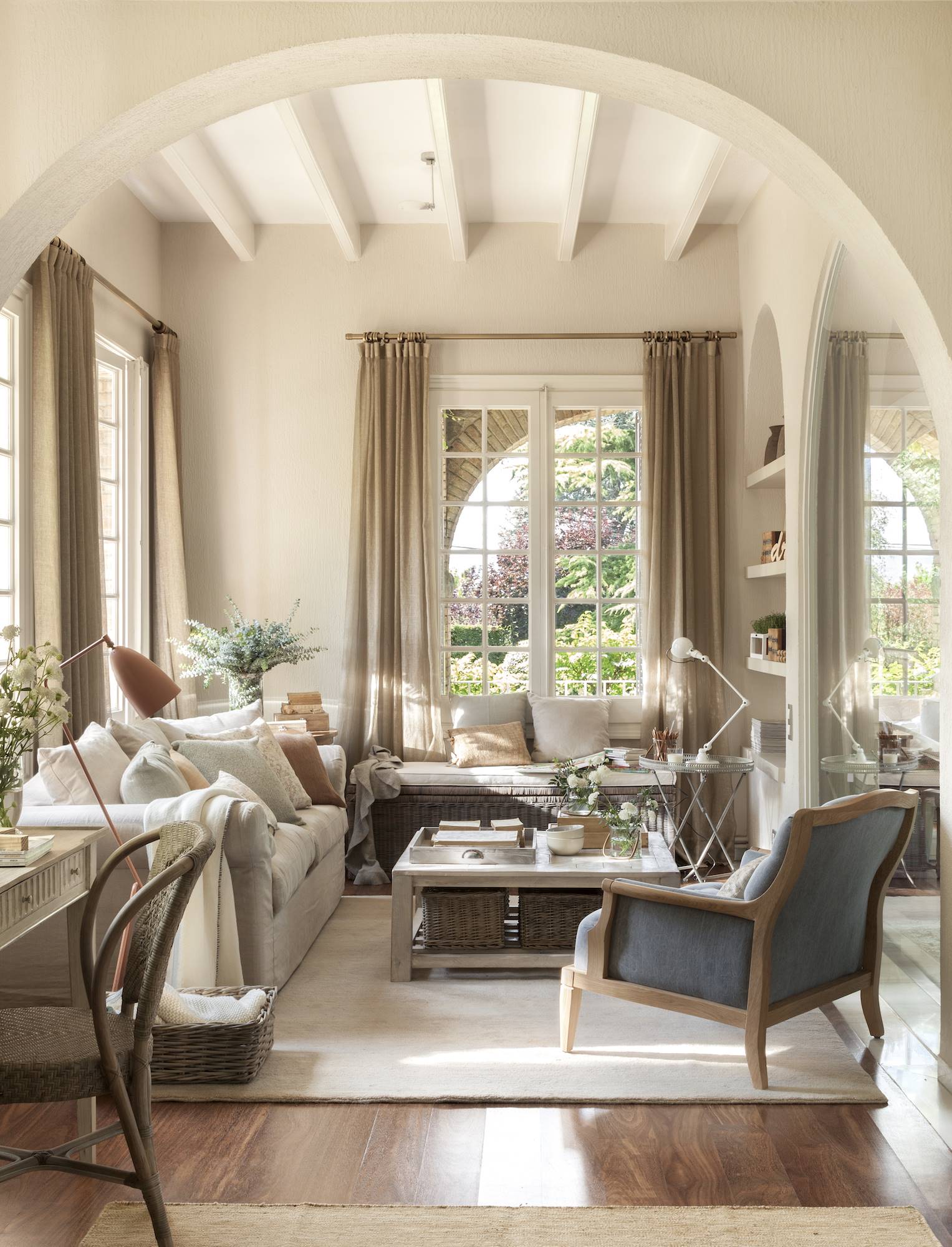 Salón con paredes y sofá en beige con butacas de color gris. 