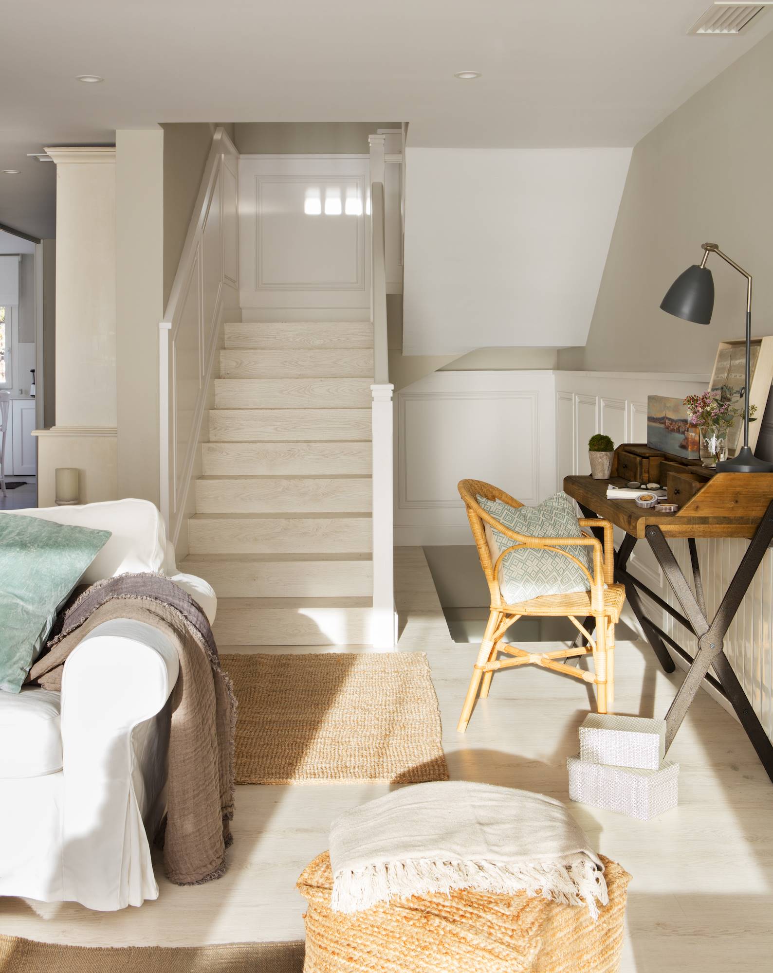 Salón con arrimadero blanco y pared beige con acceso a la escalera. 