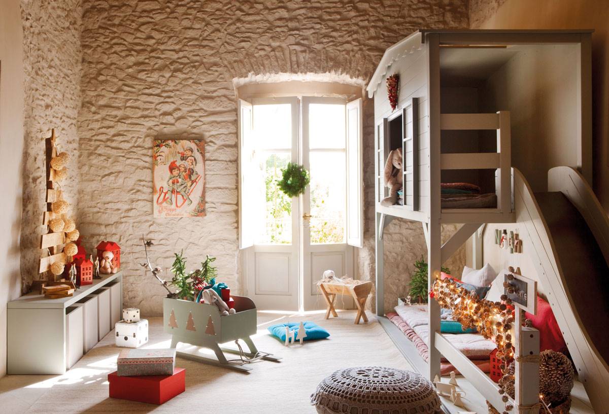 Dormitorio infantil con litera con tobogán, paredes de piedra y árbol de Navidad hecho de palés. 