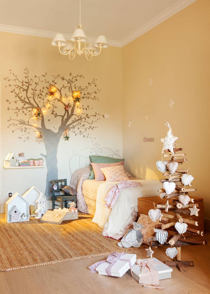 Dormitorio infantil con mini árbol de Navidad hecho de troncos y decorado con corazones.