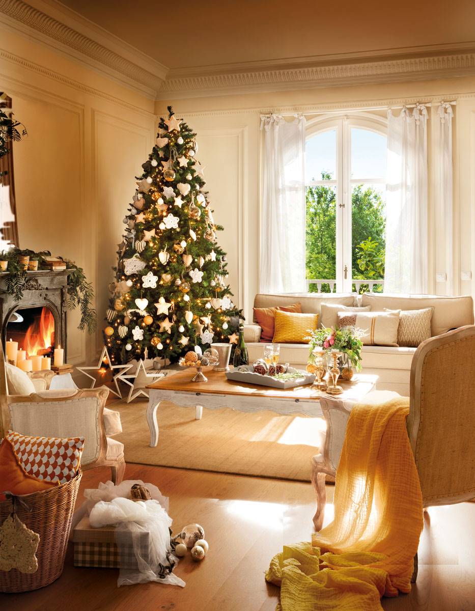 Salón con alfombra de fibras, molduras, chimenea y gran árbol de Navidad dorado y blanco. 