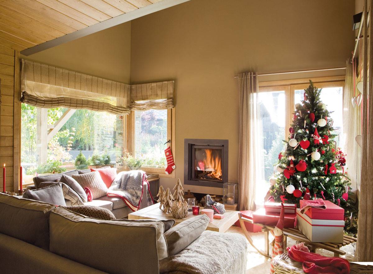 Salón de estilo rústico con chimenea y árbol de Navidad tradicional decorado en rojo y blanco. 