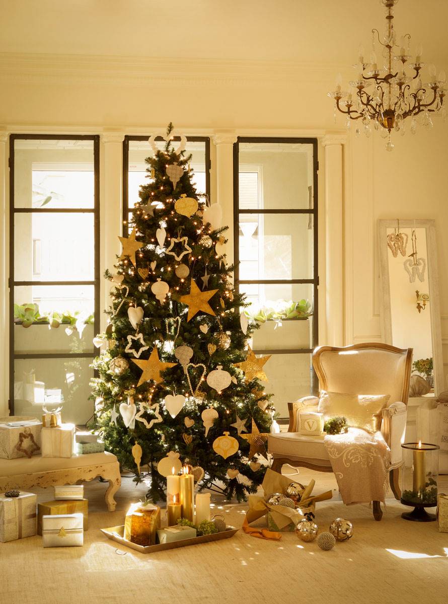 Salón clásico con lámpara de araña y árbol de Navidad con detalles dorados. 