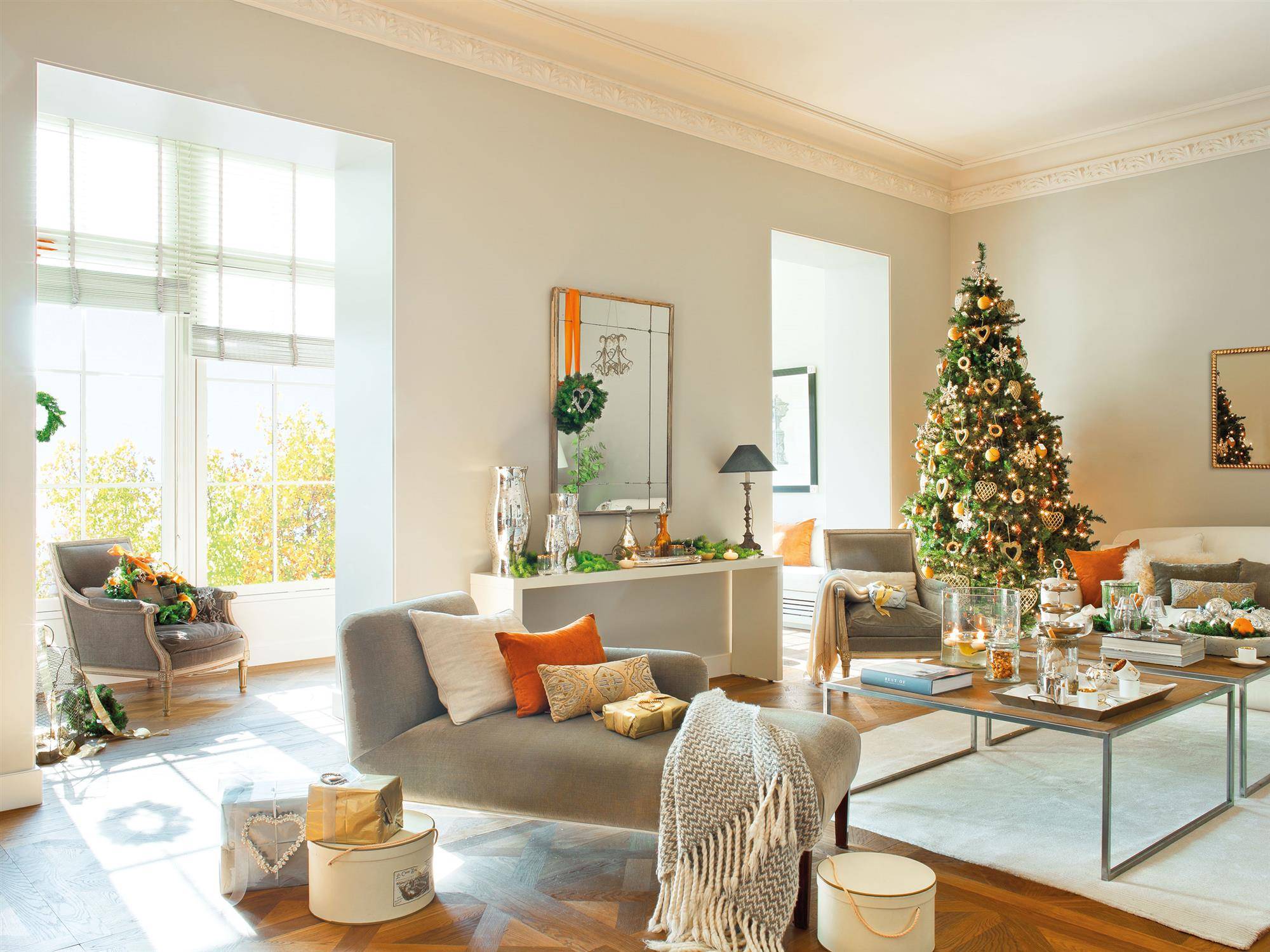 Sofá moderno decorado con sofás grises y árbol de Navidad con detalles naranjas. 