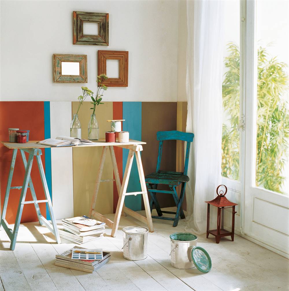 Habitación con zócalos a rayas y mesa con herramientas, botes y brochas para pintar_213963
