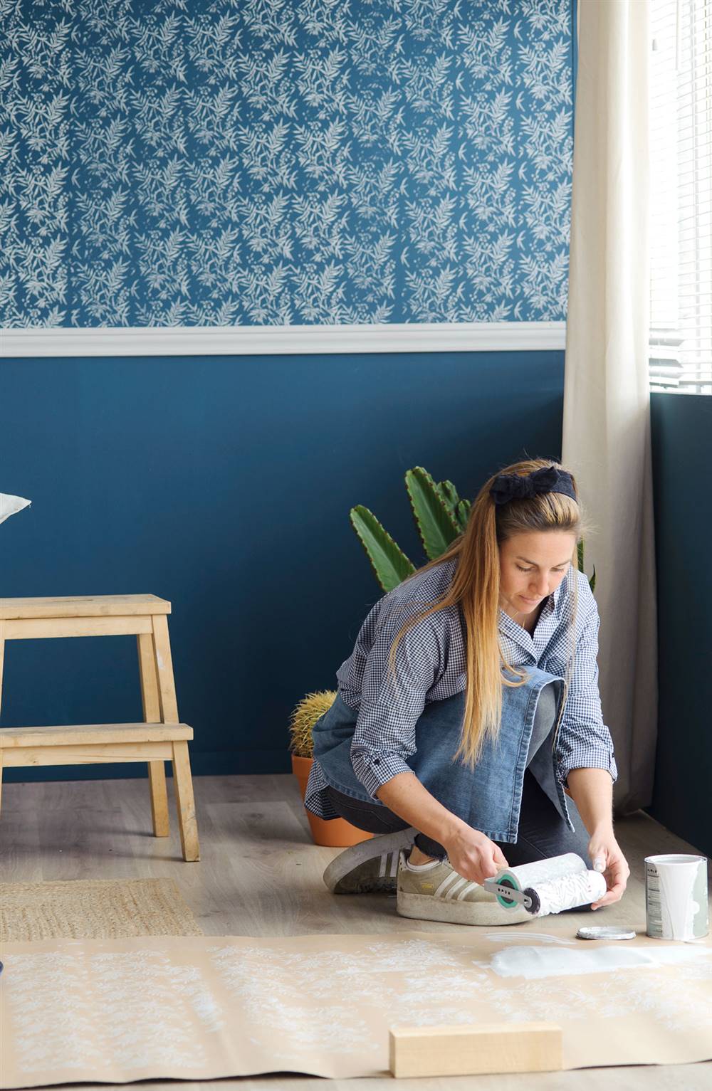 Mujer pintando la pared lisa ella misma con rodillo en azul con zócalo y estampado_451990