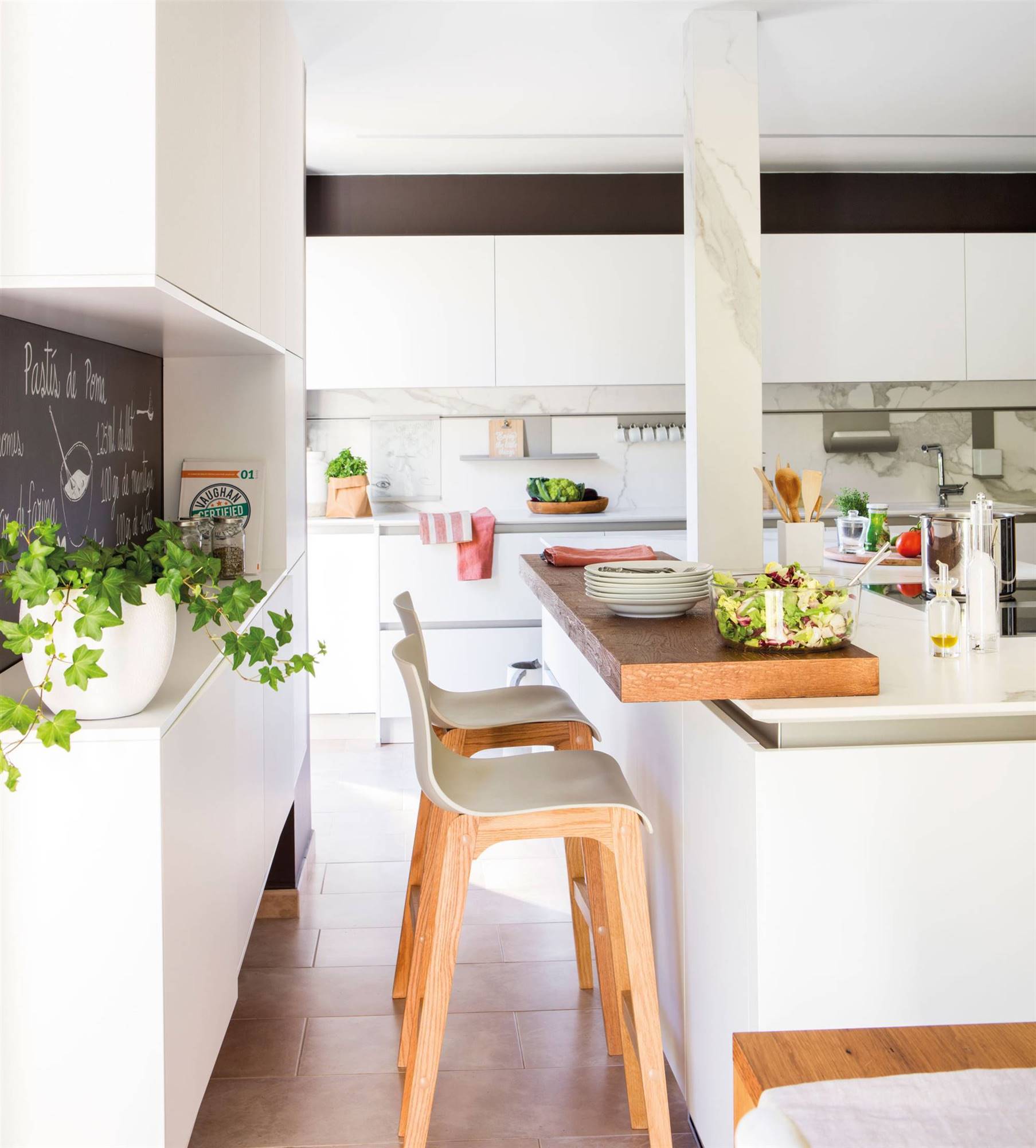 Moderna cocina con barra con mobiliario en blanco sin tiradores con frente de mármol y office integrado. 