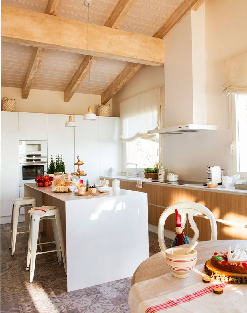 Moderna cocina de estilo nórdico con muebles de madera, vigas en el techo e isla en color blanco. 