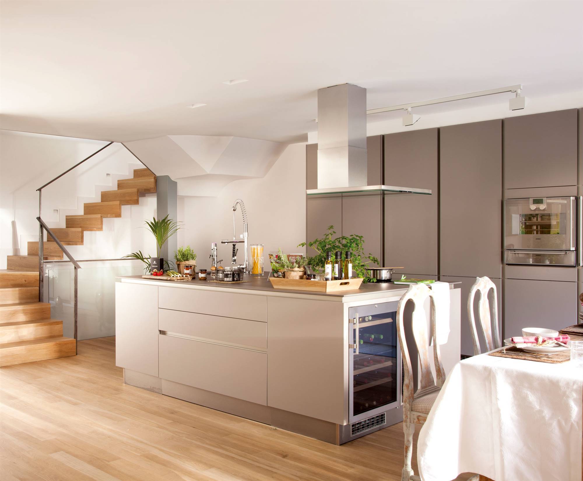 Moderna cocina de diseño con isla, electrodomésticos de acero inoxidable y muebles grises.