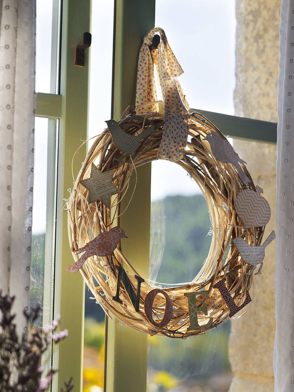 Corona de Navidad en la ventana hecha de paja y letras y adornosdecorativos.