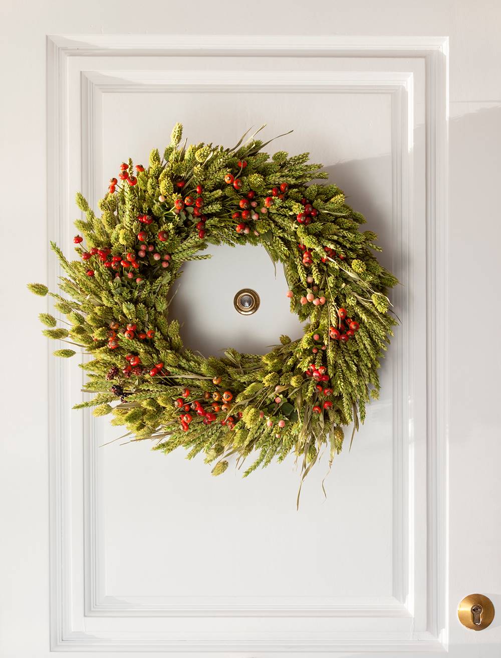 Corona vegetal navideña en la puerta.