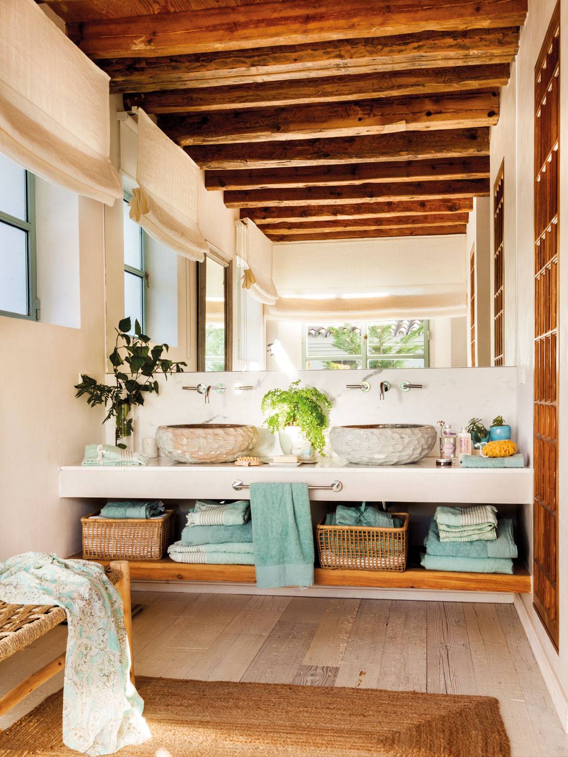 Baño con mueble de microcemento realizado a medida, techo con vigas de madera y alfombra de fibras.