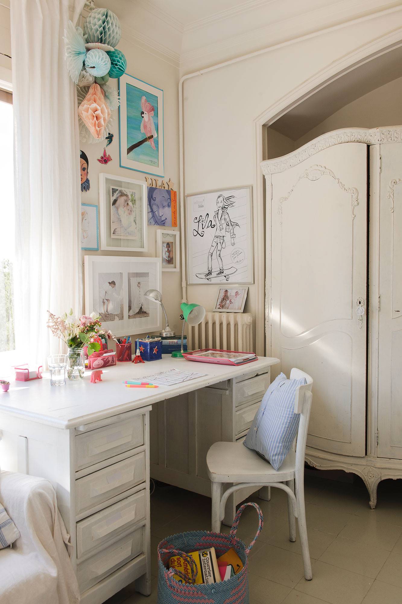 Dormitorio infantil con zona de estudio con escritorio, silla y armarios pintados de blanco.