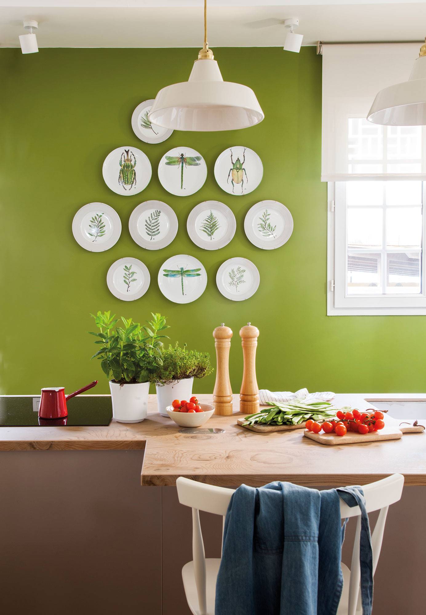 Cocina con pared verde decorada con platos y encimera de madera.