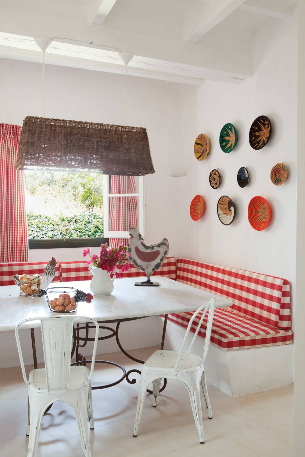 Comedor en blanco con detalles en rojo y composición de platos en la pared