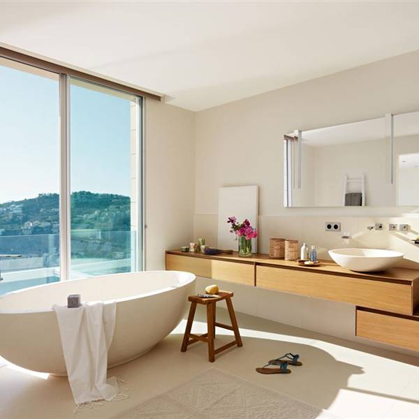 Baño con bañera, lavamanos de madera y gran ventanal