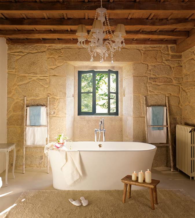 Baño con bañera y pared de piedra detrás