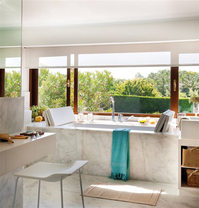 Baño con gran bañera de mármol bajo ventanal y tocador