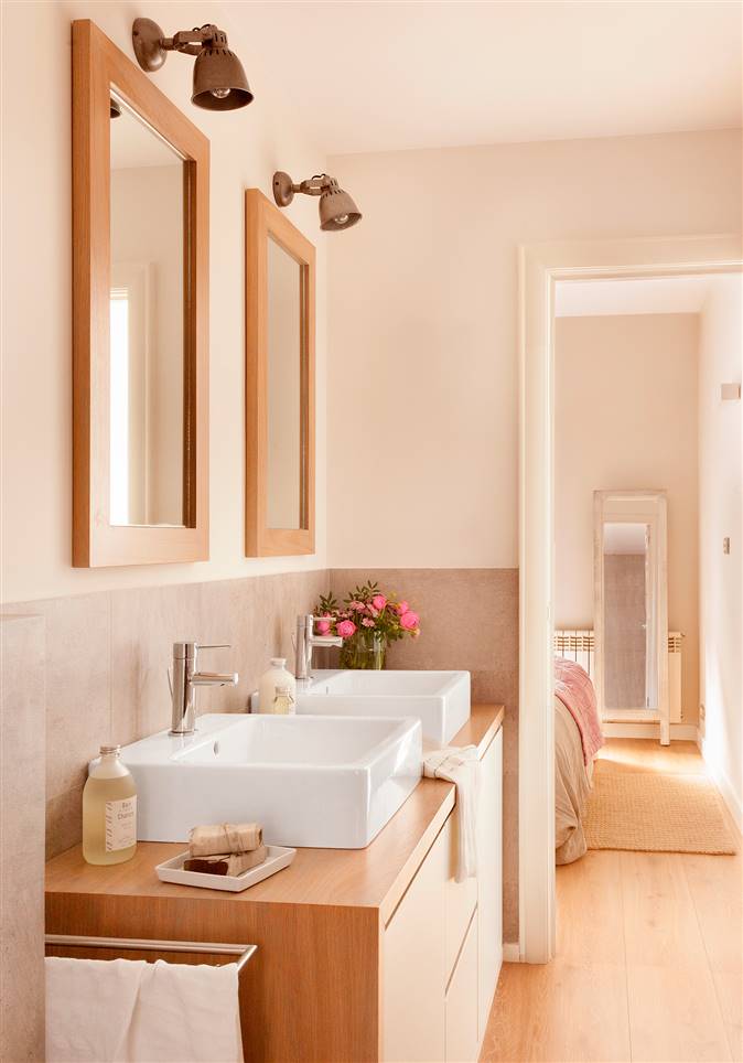 Baño con lavamanos y espejo doble sobre mueble de madera y laca