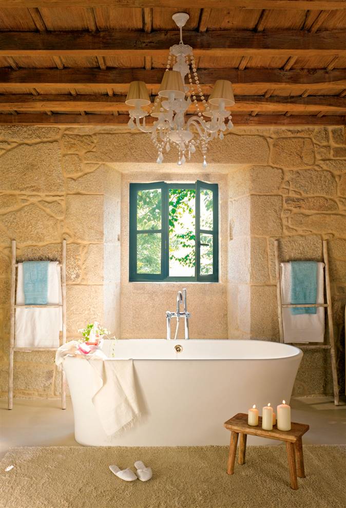 Baño rústico con bañera exenta, lámpara de techo y escaleras decorativas a ambos lados_315229