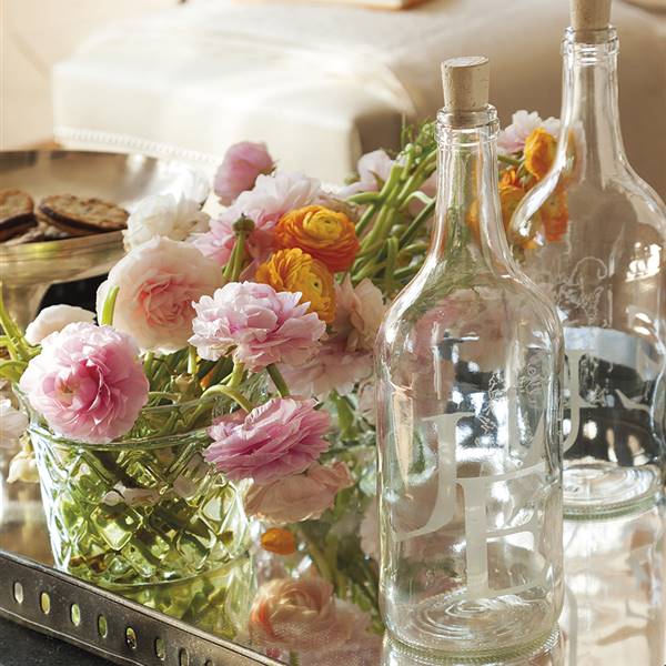 Detalle de bandeja con botellas de cristal y flores