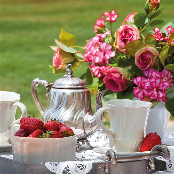 Detalle de juego de café, fresas y flores en mesita de jardín