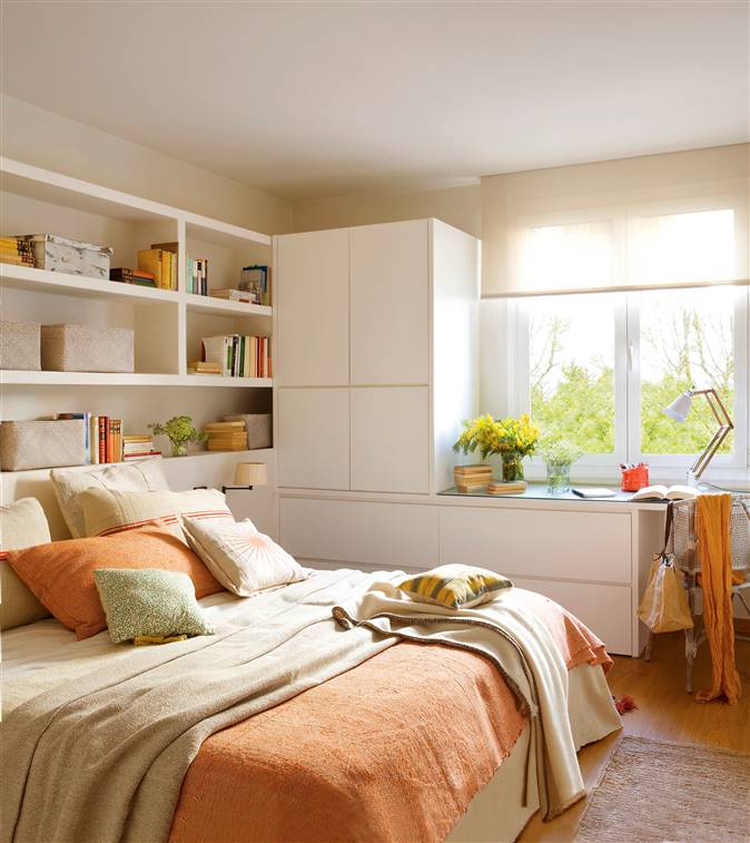 Dormitorio con cabecero a medida en forma de estantes y armarios y cómoda