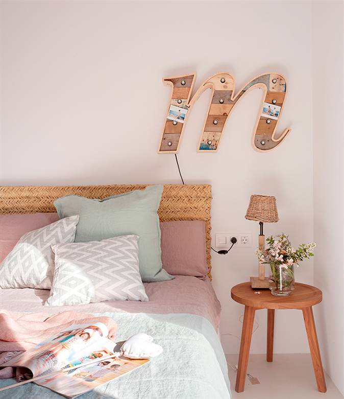dormitorio con cabecero de fibra natural y sábanas en rosa y verde