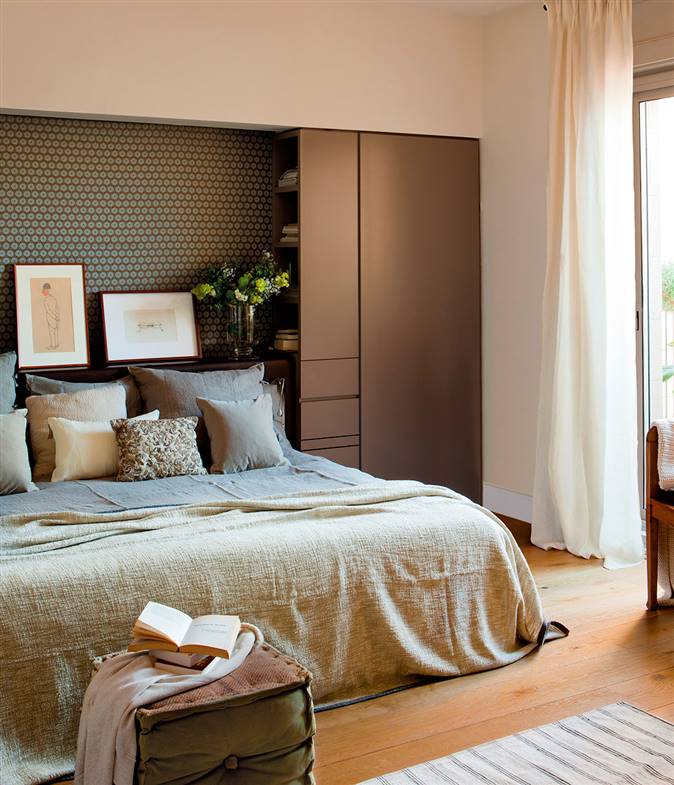 Dormitorio con hueco en el cabecero y mueble a medida en color marrón oscuro