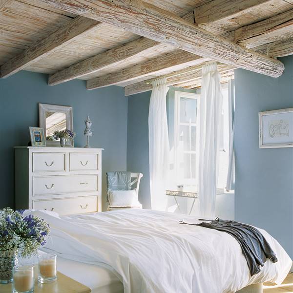 Dormitorio con paredes en color azul y techo de vigas vistas