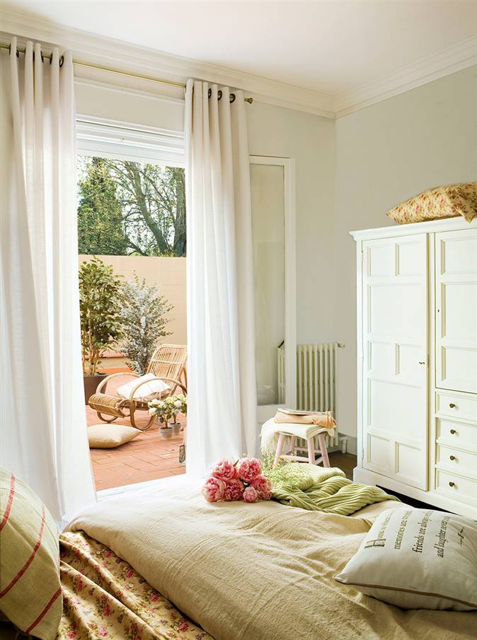 Dormitorio con salida a la terraza  y ramo de flores sobre la cama