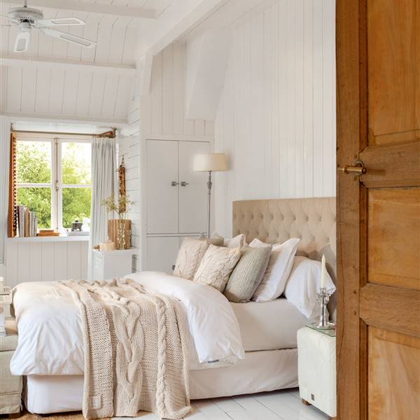 Dormitorio con vigas blancas y ventilador cabecero en tonos beige_408203