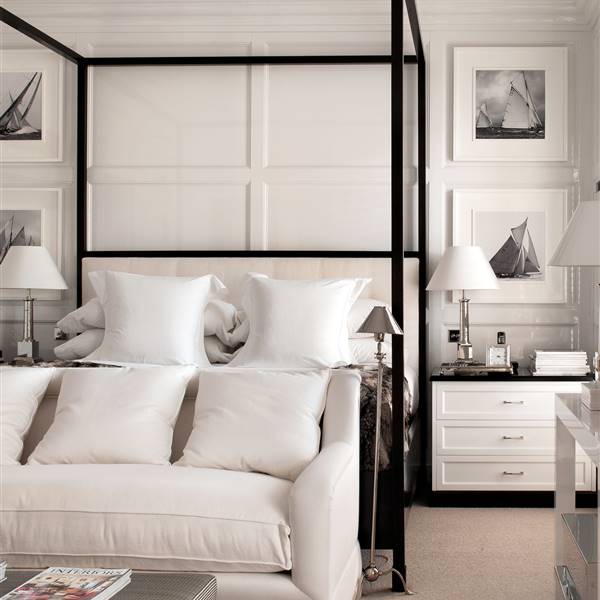 Dormitorio en blanco y negro con cama con dosel, paredes con cuarterones y cuadros_327830