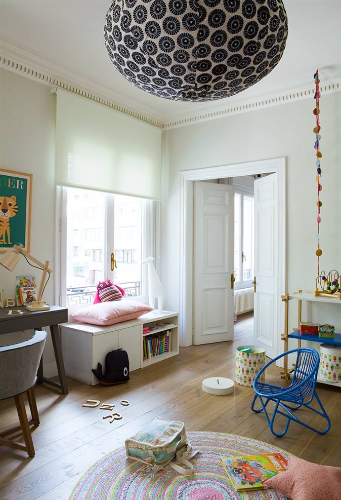 Dormitorio infantil con lámpara globo de papel y banco bajo la ventana
