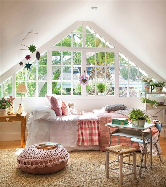 Dormitorio infantil con ventanal triangular y puf de ganchillo