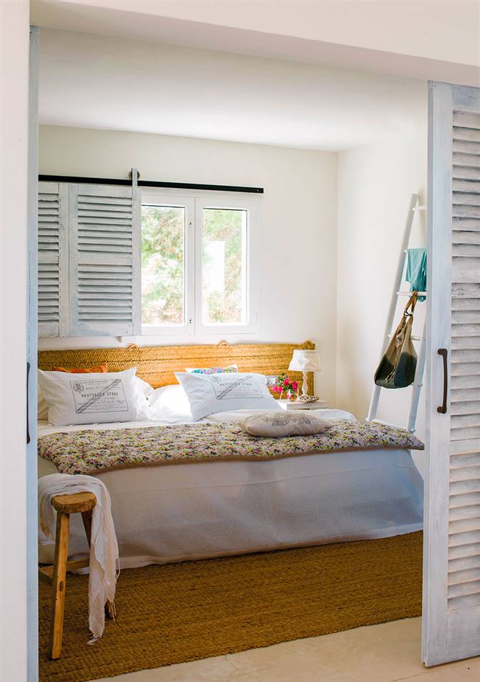 Dormitorio pequeño de estilo rústico en blanco con cama, cabecero y alfombra de fibras naturales