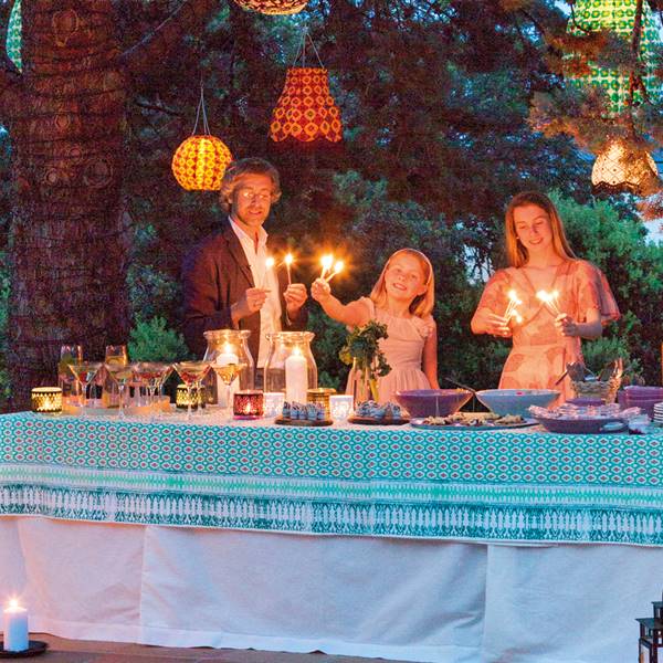 Fiesta de noche en el jardín de Lorenzo Meazza con mesa de celebración y faroles de luz colgados de los árboles