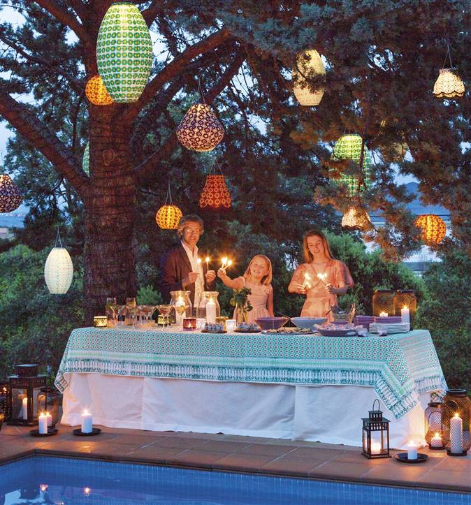 Mesa de fiesta puesta junto a a la piscina con farolillos y velas