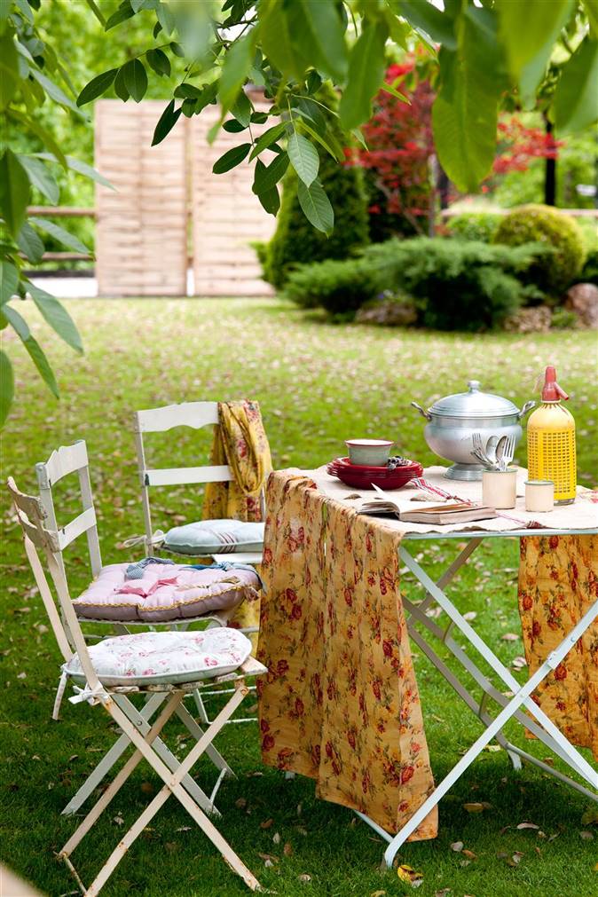 Mesa de tijera con camino de mesa estampado y sillas en el jardín