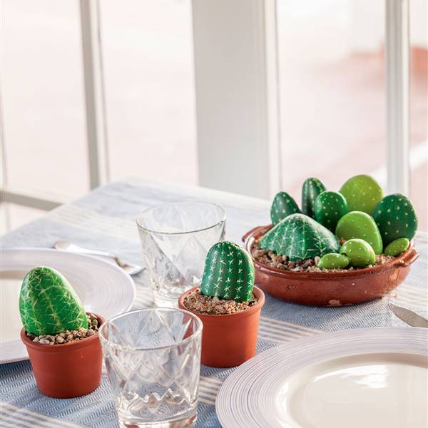 Mesa decorada con macetas de cactus hechos con piedras pintadas