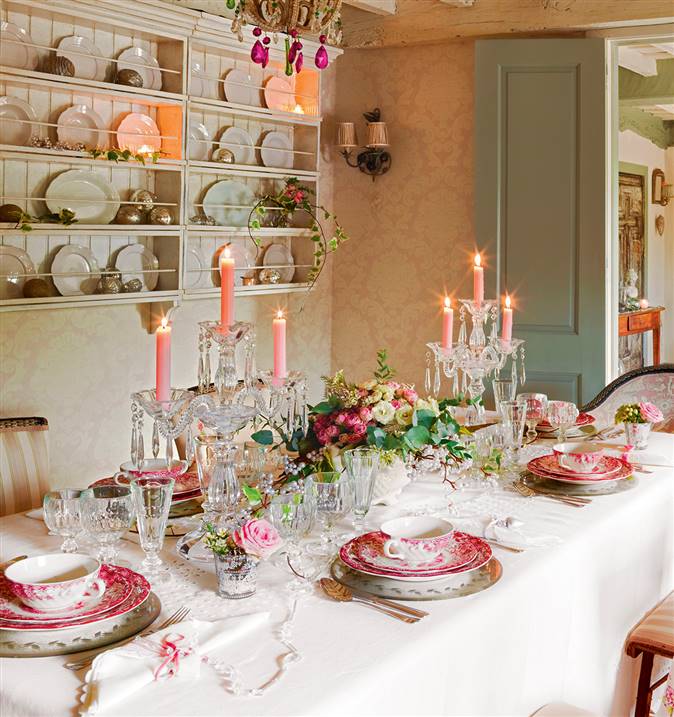 Mesa lista para celebrar con vajilla historiada y velas rosas