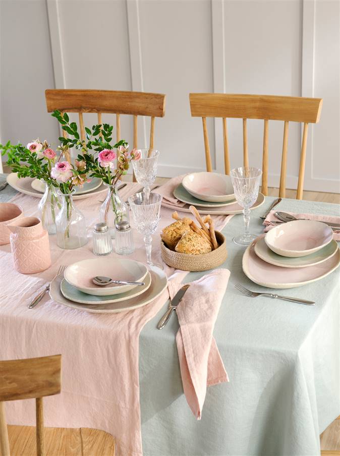 Mesa vestida con manteles y camino de mesa en tonos pastel rosa y verde menta con vajilla, copas de cristal tallado y flores_480319
