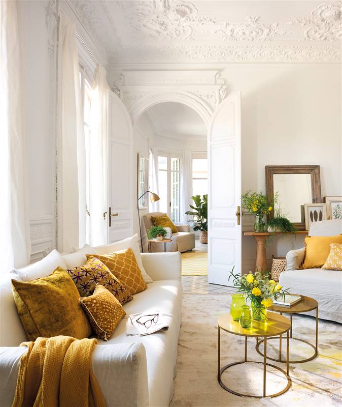 Salón blanco con sofá y butaca blanca con cojines amarillos y dorados_ 00454744
