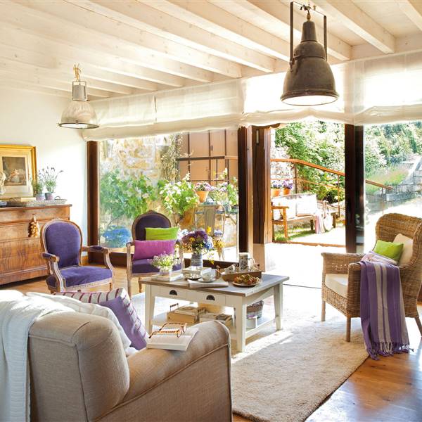 salón con butacas de terciopelo violeta, mesa de centro de madera blanca y lámparas de estilo industrial