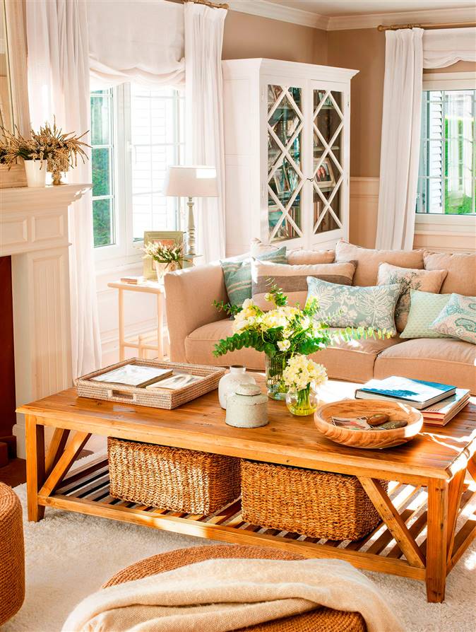Salón con mesa de centro de madera, sofá gris, vitrina blanca y cestas de fibra natural