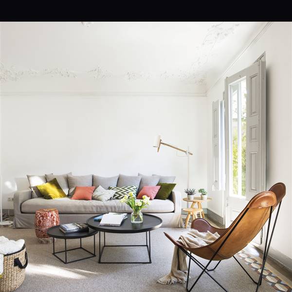 Salón con pared y sofá gris, silla butterfly, mesas de centro de metal y lámpara de pie_piso Bárbara Aurell