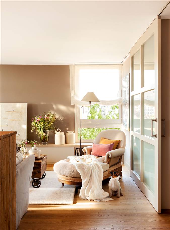 Salón con paredes en beige, suelo de madera, chaise longue y puerta corredera