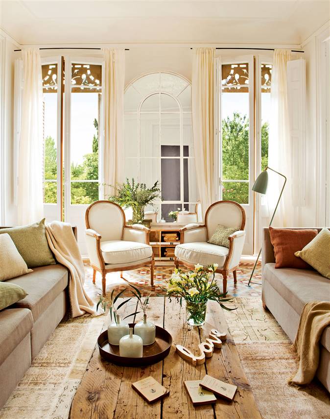 Salón en finca regia con grandes ventanales y distribución simétrica con dos sofás enfrentados y dos butacas