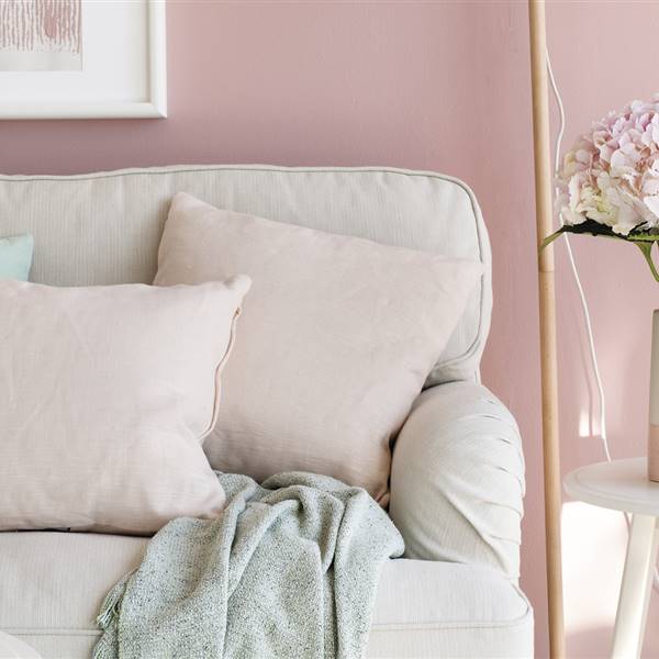 Salón en rosa palo, blanco y turquesa, con sofá, cojines, mesita auxiliar, flores, jarrones y cuadro